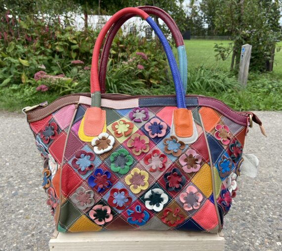 Mooie leren tas met bloemen detail in verschillende kleuren, elke tas is uniek. Binnenin de tas zitten drie vakken waarvan twee los en 1 met rits. Tijdloos en duurzaam.